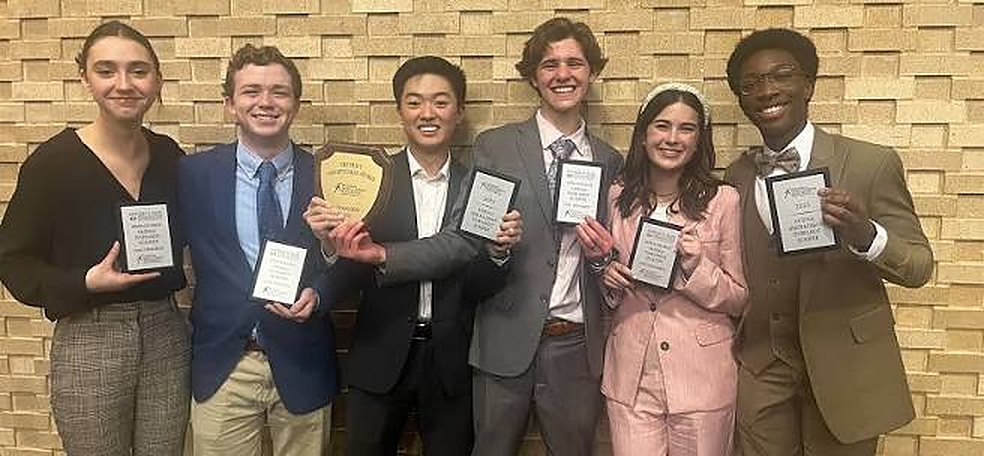Six students in suits and blazers holding award plaques