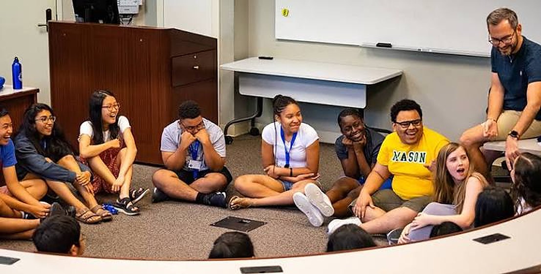 A coach leading a discussion with students seated in a circle